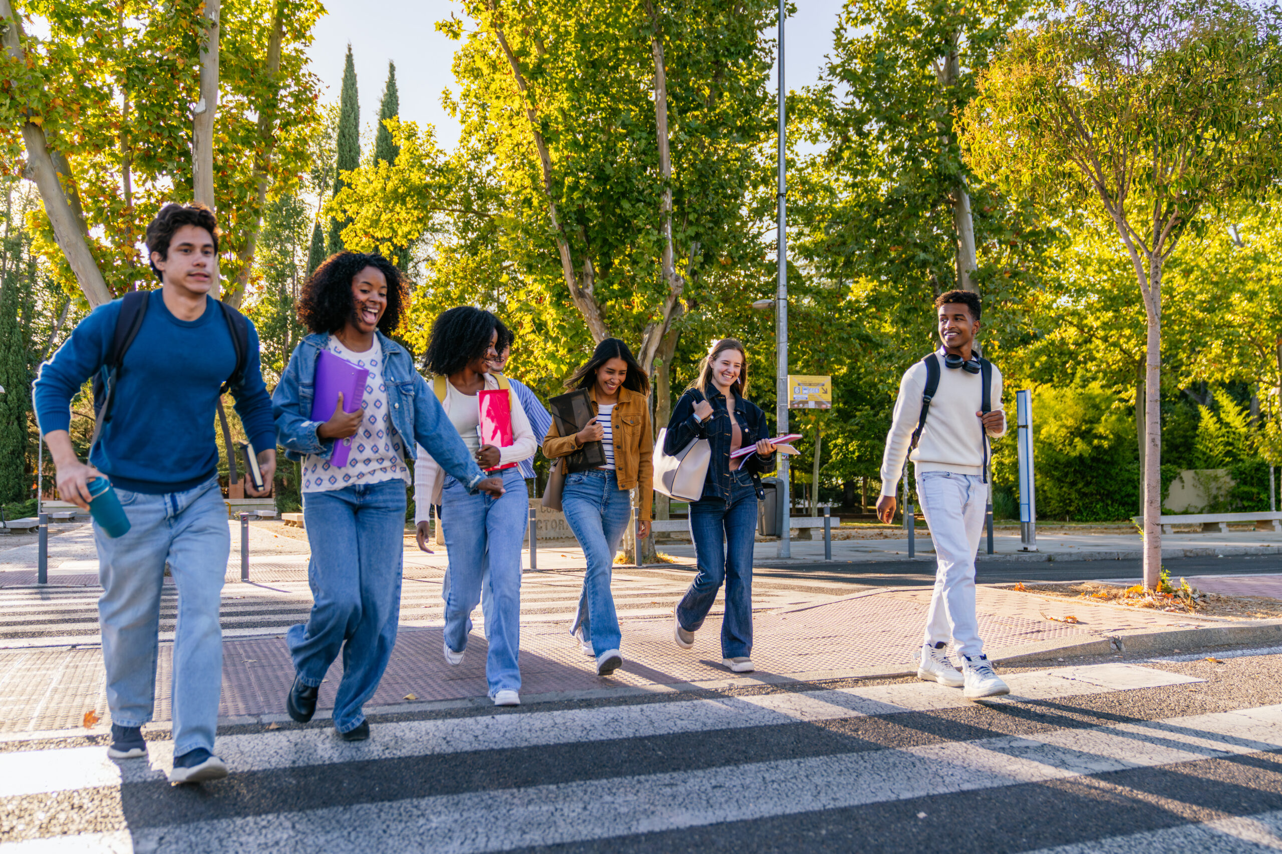 Group of diverse university students walking together on a pedestrian crossing, heading to or from classes on a sunny day